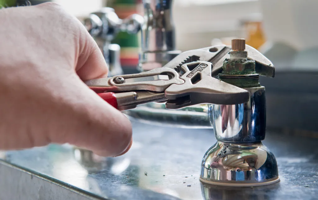 Plumber repairing a kitchen sink faucet