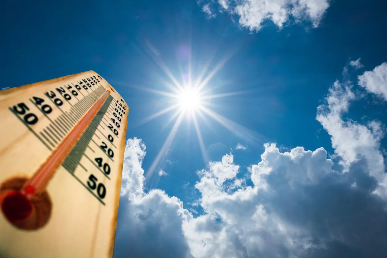 Photo of a thermometer with a high temperature set against the background of a hot summer day.